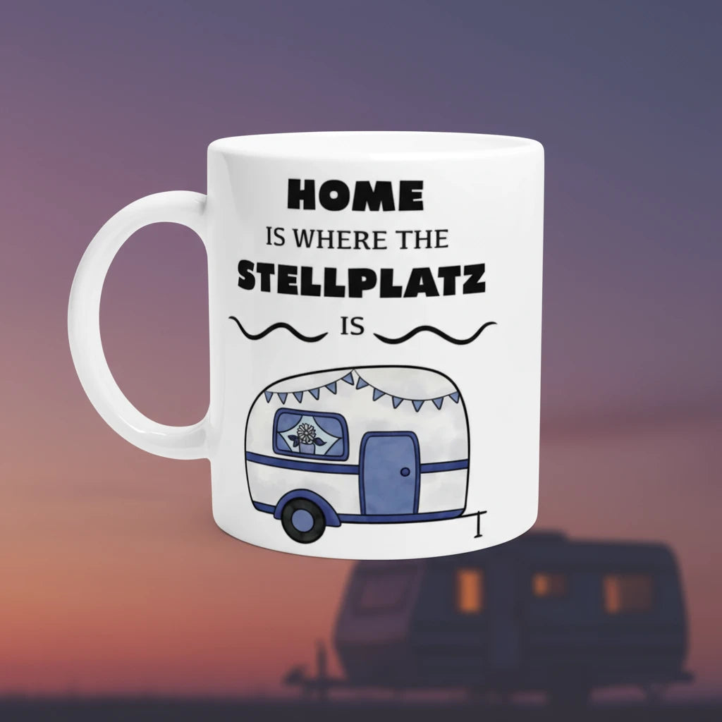 Weiße Tasse mit blau-weißem Wohnwagen und Spruch „Home is where the Stellplatz is“. Camping-Tasse für Wohnmobil- und Vanlife-Fans.