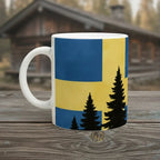 Weiße Keramiktasse mit illustrativem Flaggenmotiv von Schweden und Waldsilhouette im skandinavischen Design.