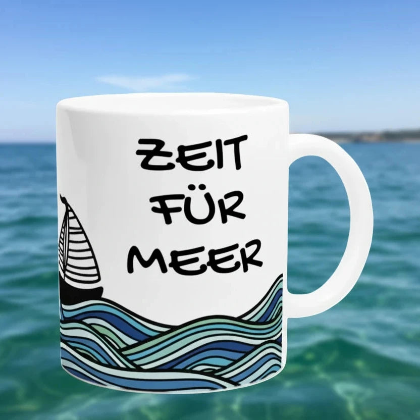 Weiße Keramiktasse mit maritimem Segelboot- und Wellenmotiv sowie dem Schriftzug „Zeit für Meer“ in Schwarz
